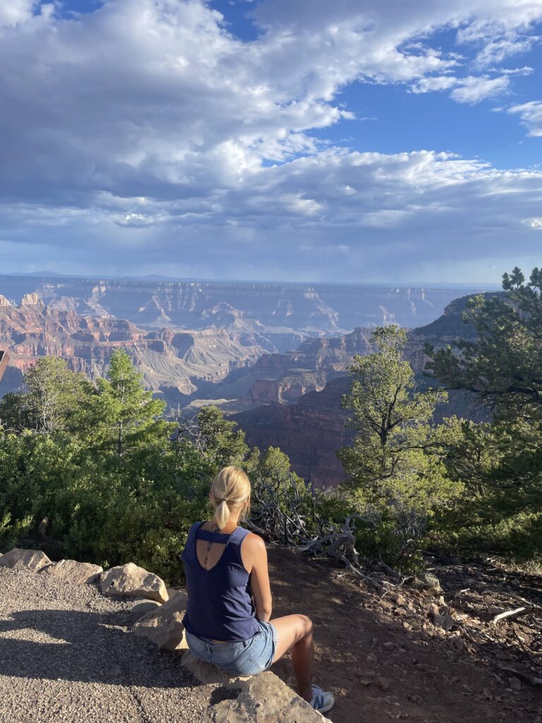 Woman sitting at a viewpoint overlooking the Grand Canyon North Rim in Arizona.
